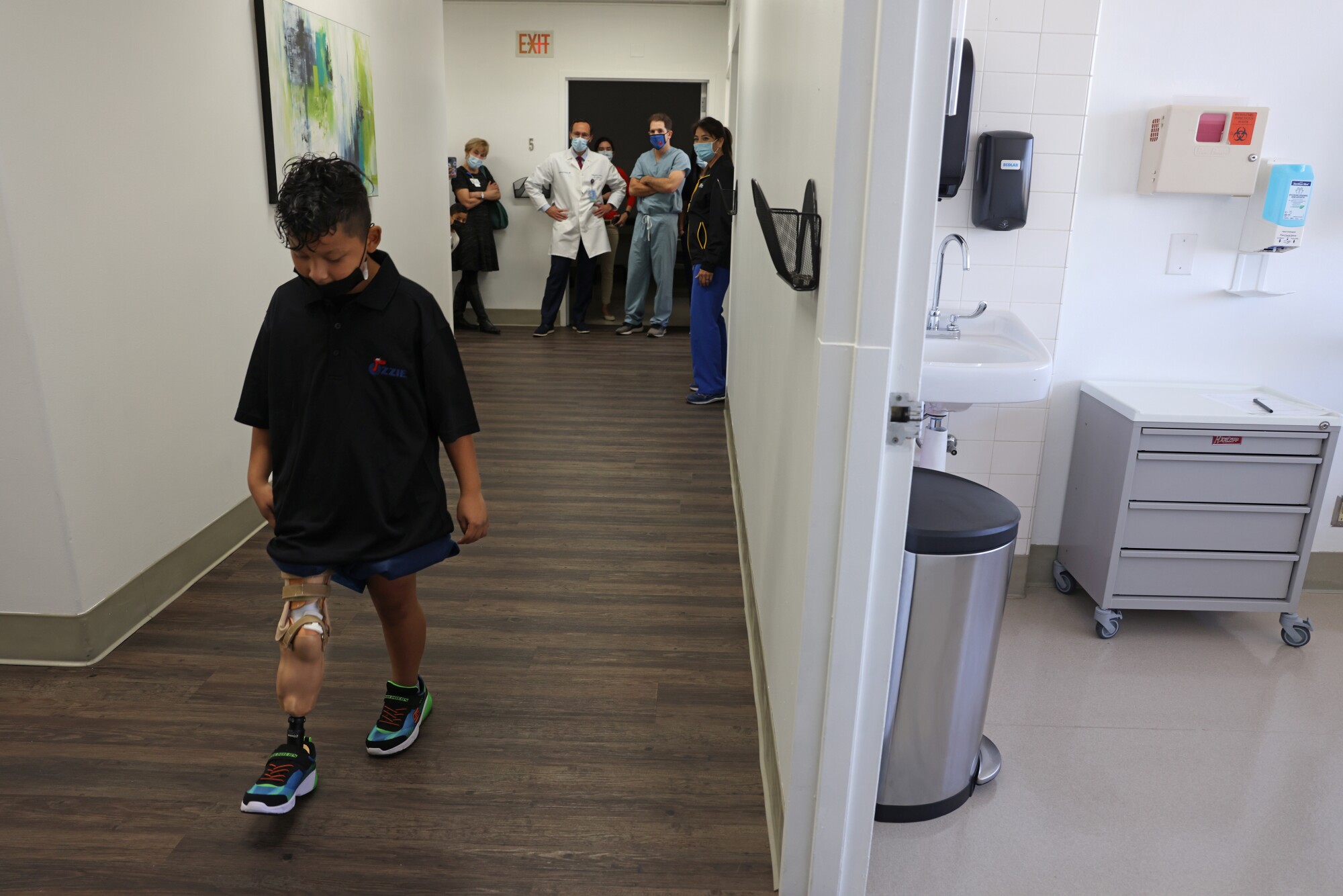 Medical staff looks on as Efraín walks with his prothesis 