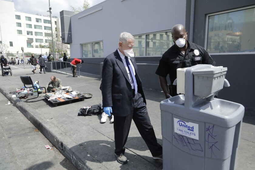 A police officer and a man in a suit walk along skid row