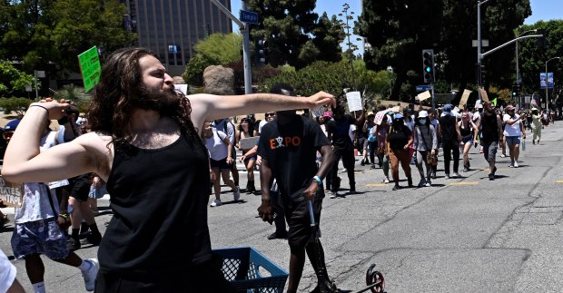 A activists tosses a projectile toward the LAPD as they...