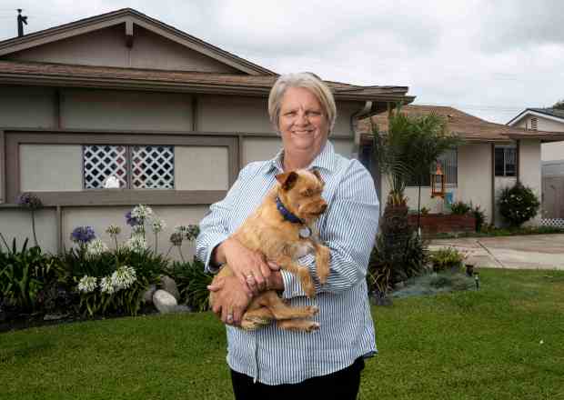 Debbie Marcusson, 55, holds her dog, Baron, in front of...