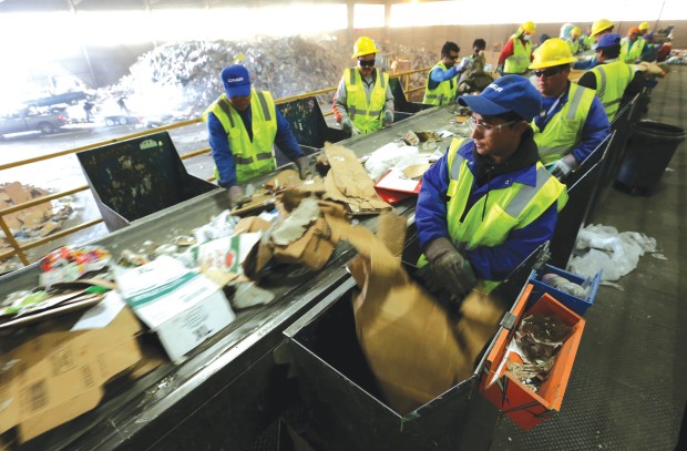 Employees work to separate recyclable cardboard from trash at a...