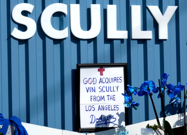 A note in a frame “God Acquires Vin Scully From...