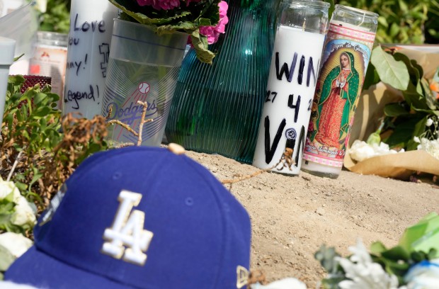 Fans leave baseballs, notes, flowers, hats, candles, flags, as they...