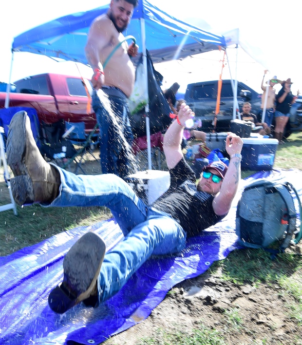 A country music fan cools off by sliding on a...