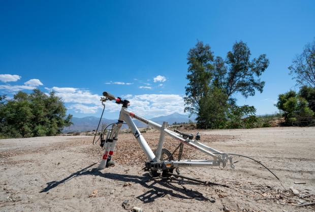 A bike frame stands alone alongside a drainage ditch where...