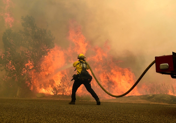 A Cal Fire firefighter works to keep flames from the...
