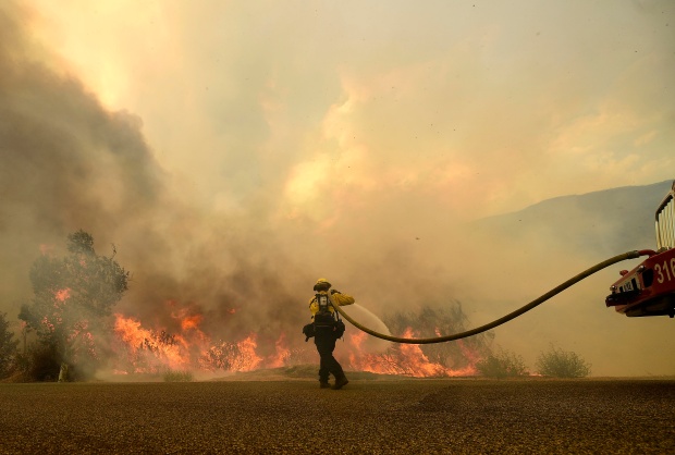 A Cal Fire firefighter works to keep flames from the...
