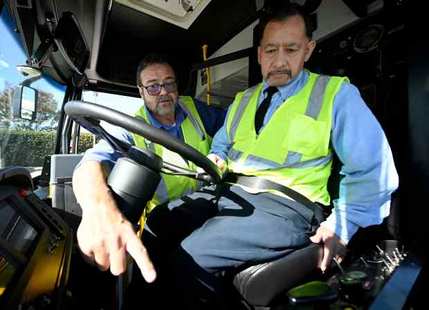 Foothill Transit bus driver Refugio Dimas, right, receives instructions on...